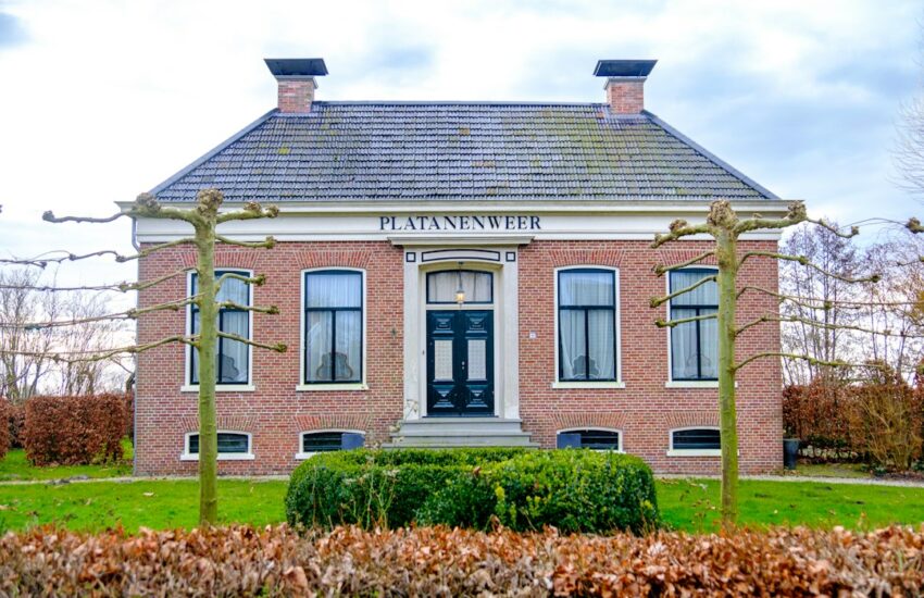 Red brick house with two chimneys and manicured bushes