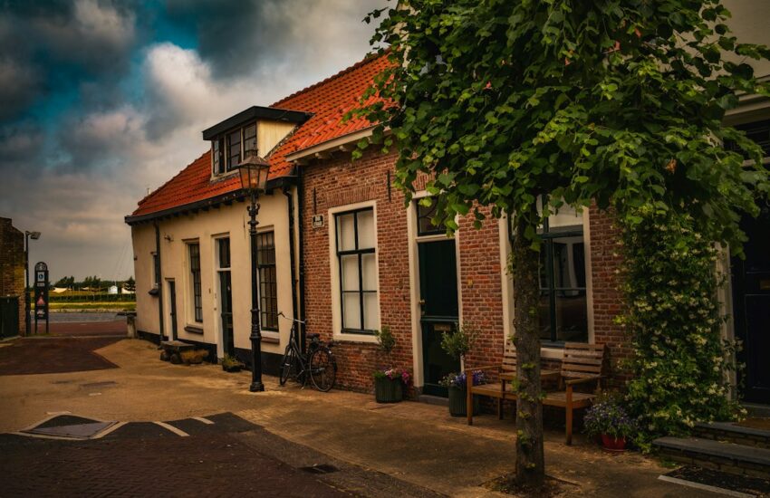 a brick building with a red roof and a tree in front of it